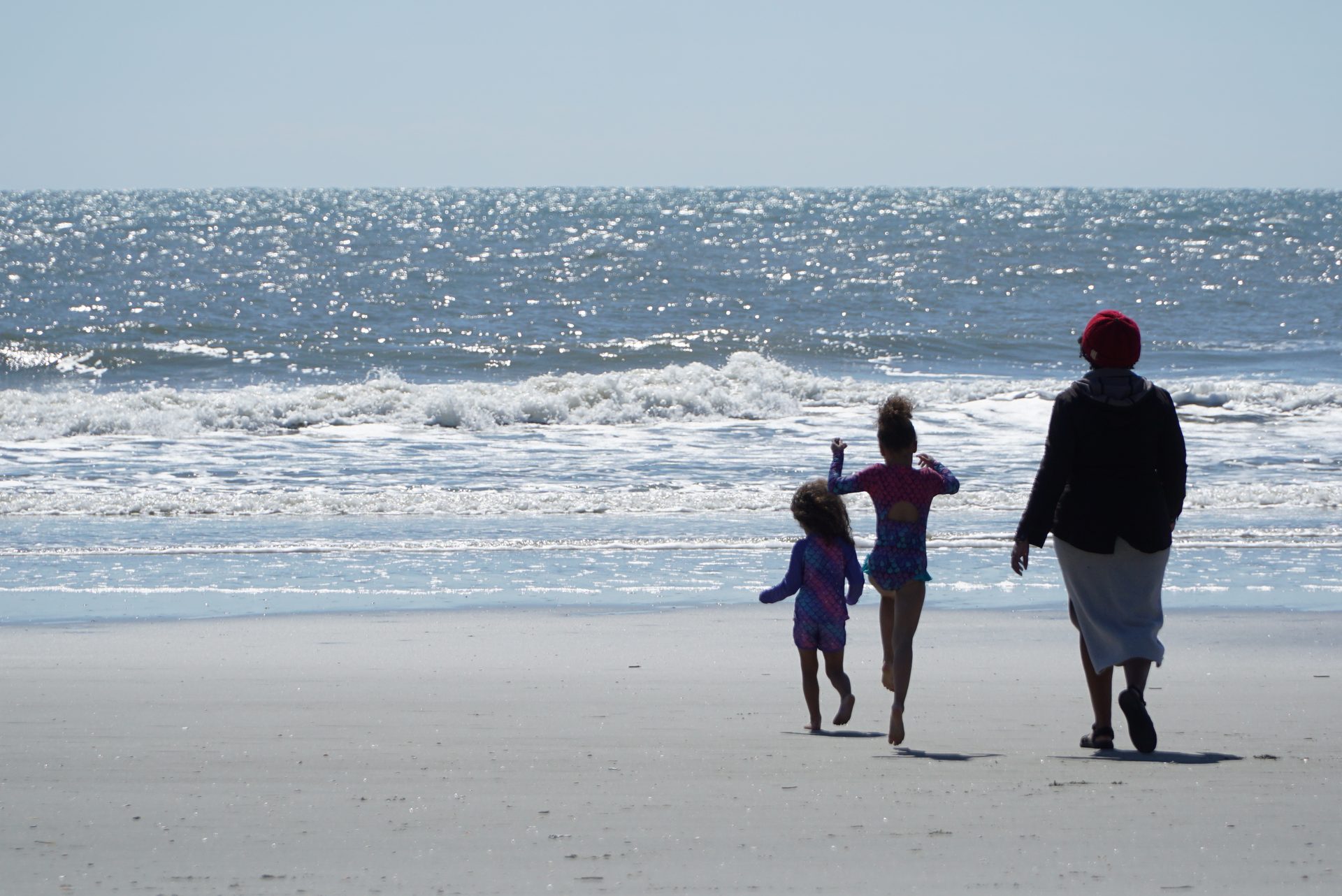Family silhouette walking toward the Atlantic Ocean at Folly Beach