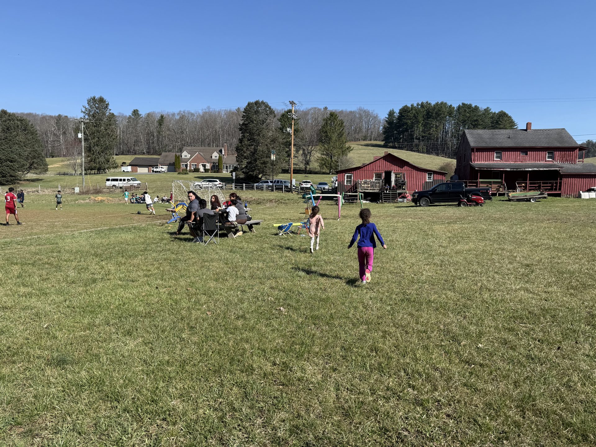 Soccer match in the backyard of a country diner near Galax, Virginia — players in the field behind a red barn