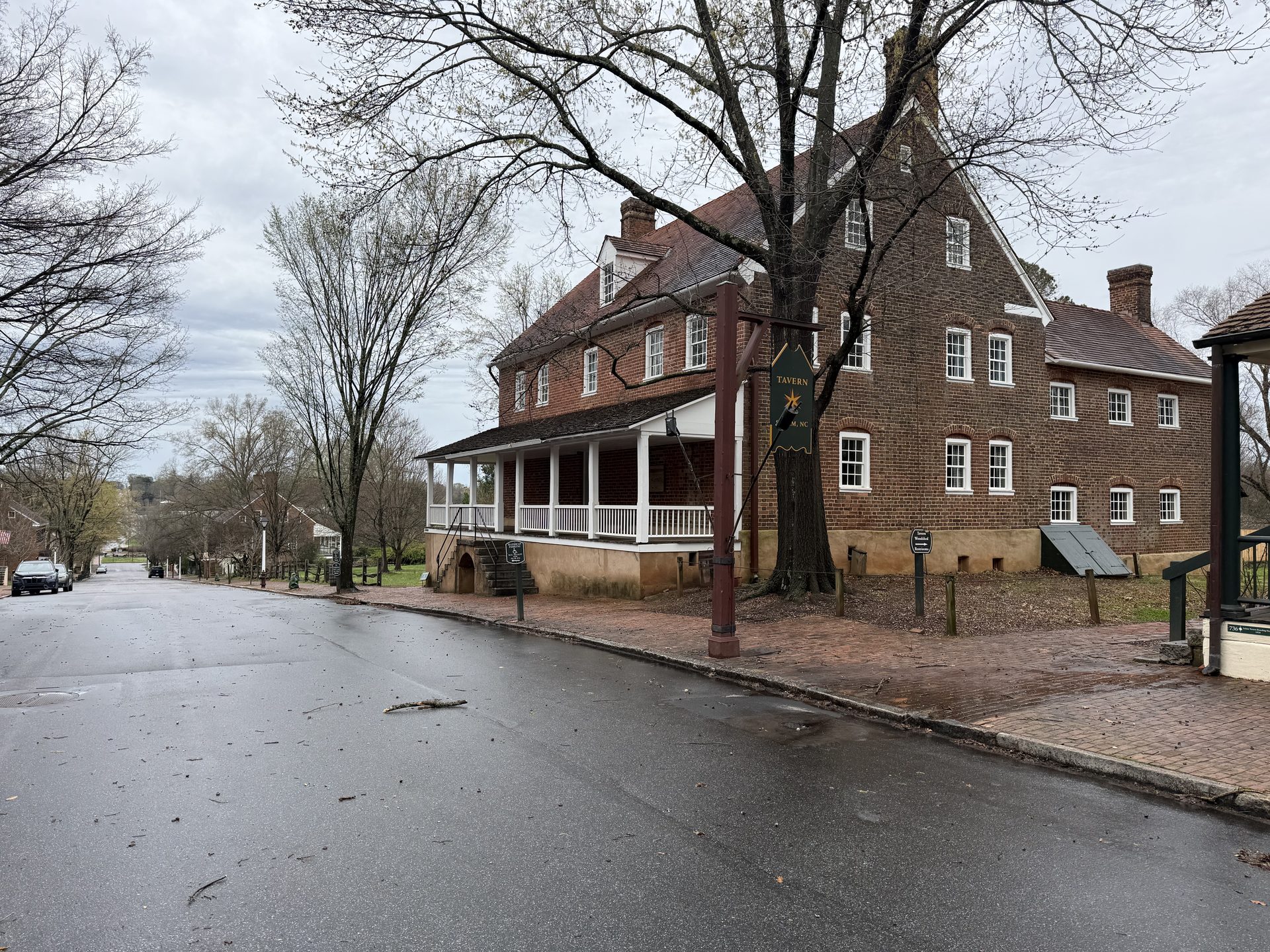 Large three-story Moravian-era brick building in Old Salem on a rainy overcast day