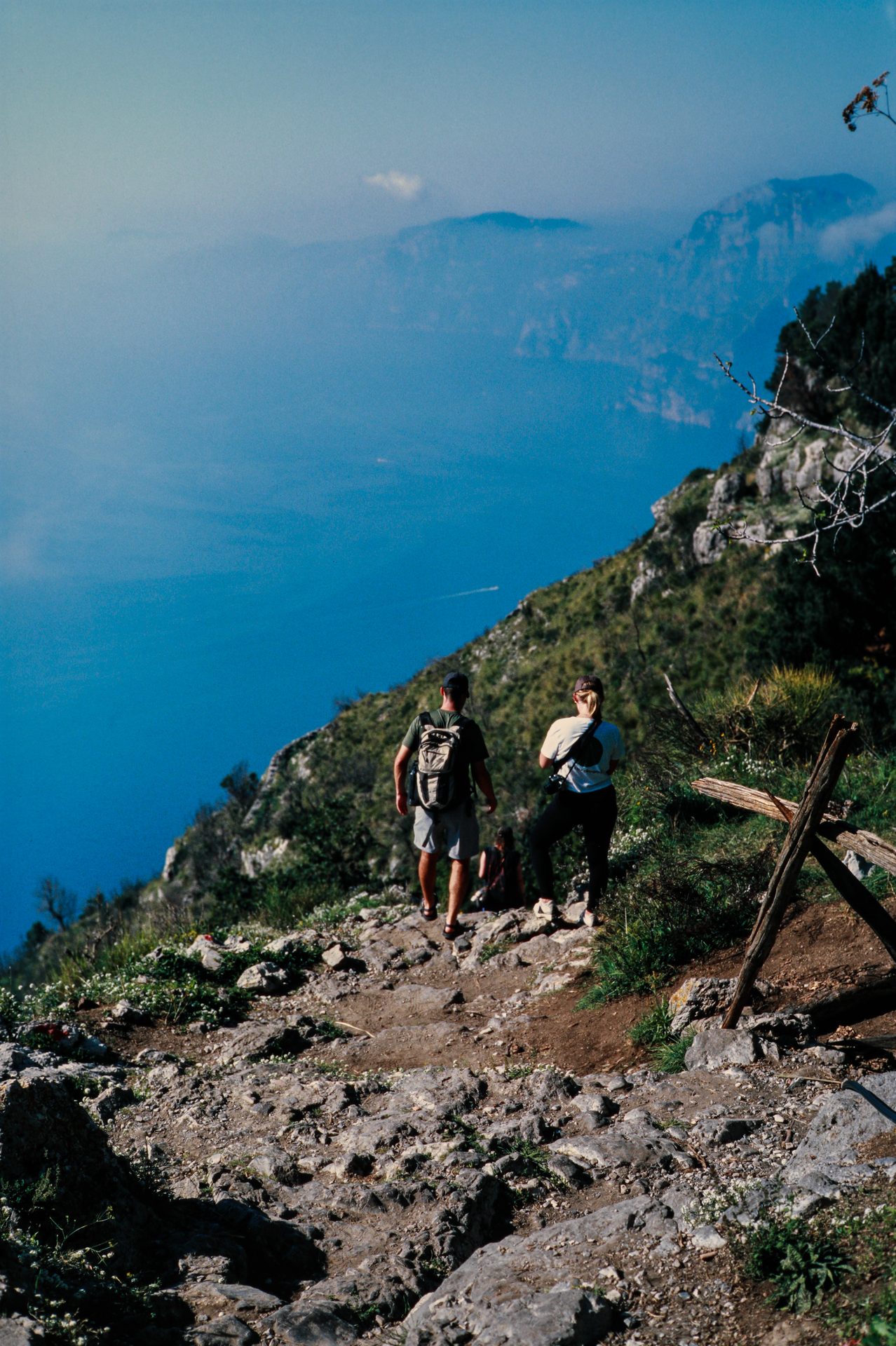 Two hikers on a clifftop trail above the Amalfi Coast — 35mm film