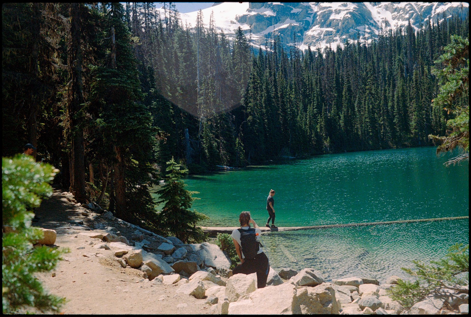 Two hikers on the shoreline of Joffre Lakes, glacial water and mountains behind — Kodak Portra 800