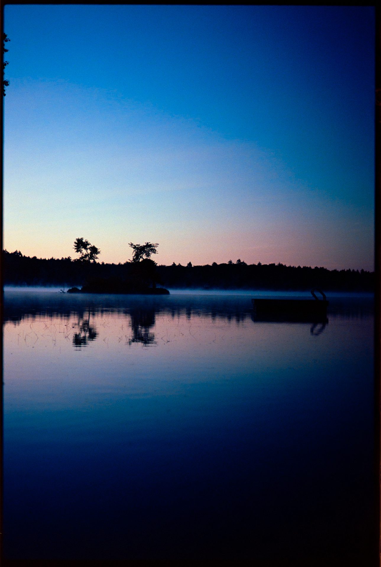 Maine lake at blue hour — island silhouetted against pink and blue sky, mist on the water — Kodak Ektar 100