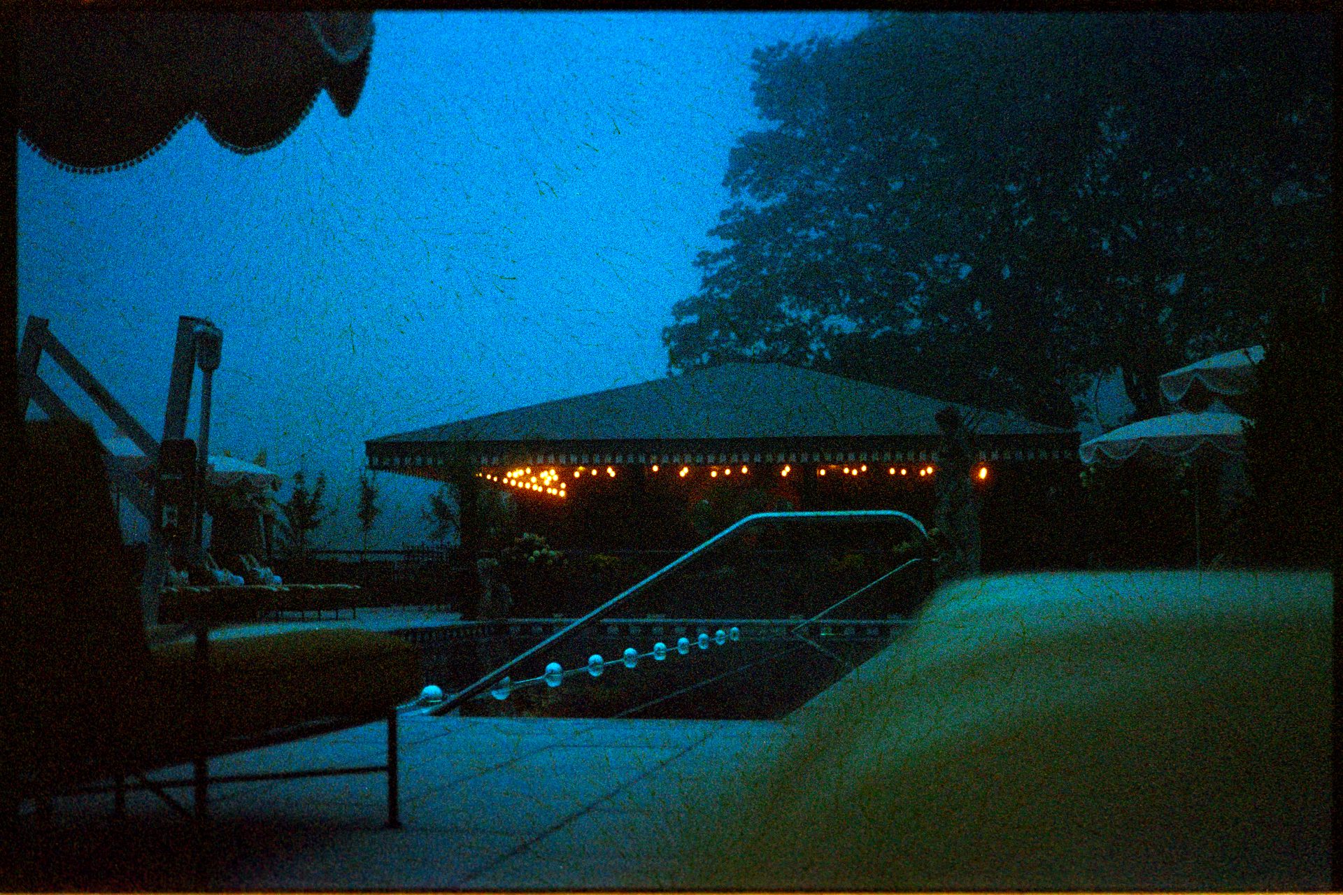 Maine hotel pool at blue hour — string lights reflecting on still water — Kodak Gold 200