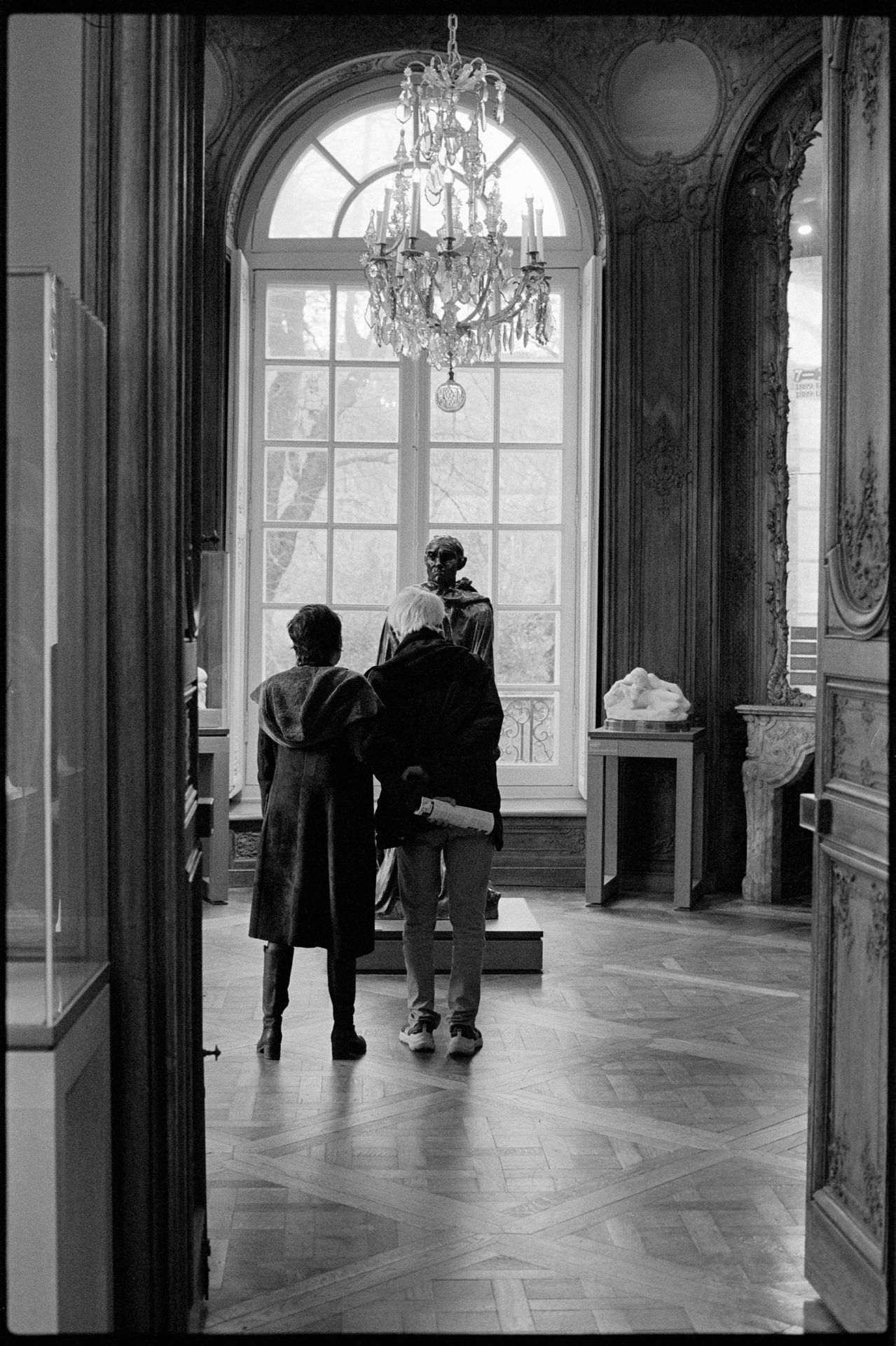 Interior of the Musée Rodin, Paris — chandelier and stone archway, figures in gallery — Ilford HP5