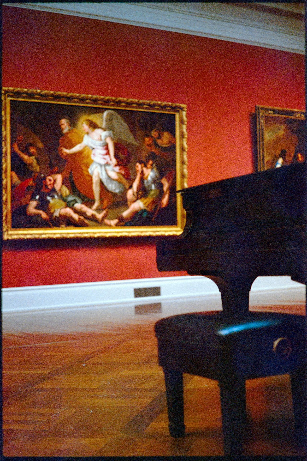 Grand piano in front of an old master angel painting on a red wall, Toledo Art Museum — Kodak Portra 800