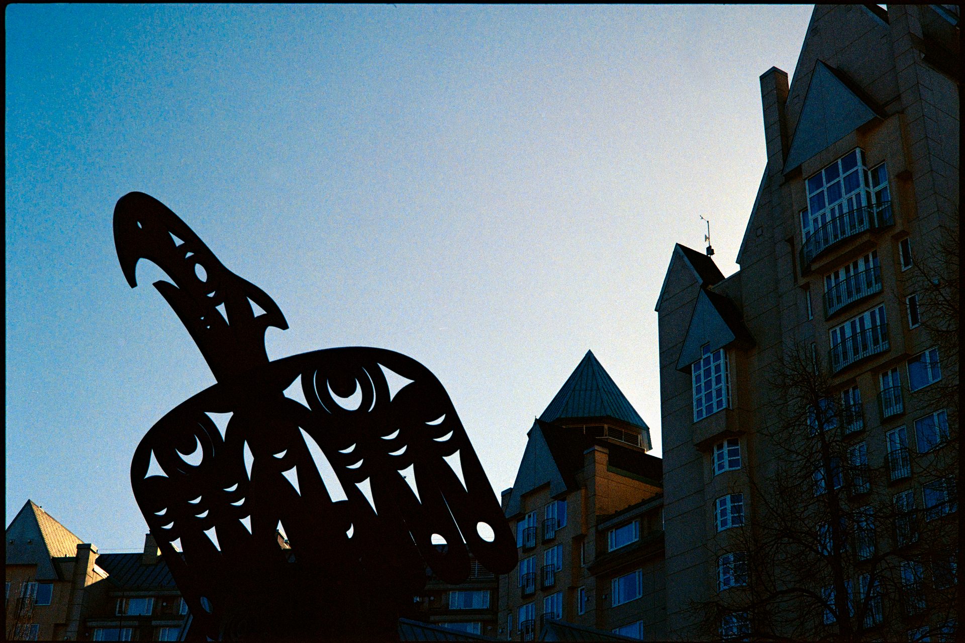 Indigenous raven sculpture silhouetted against dusk sky, Whistler Village — Fuji 400