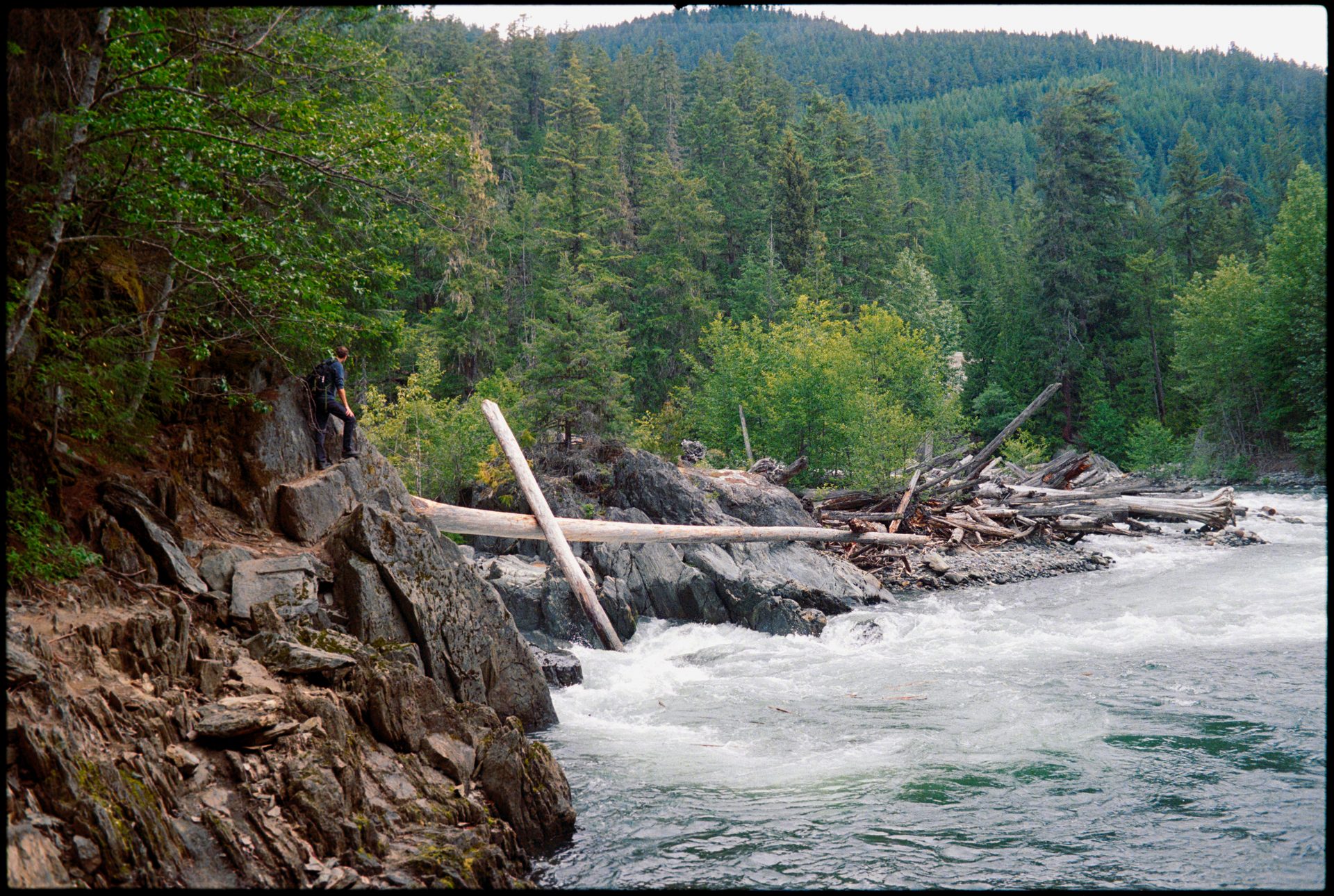 Hiker on rocky shoreline above a rushing glacial river, Whistler — Kodak Portra 800